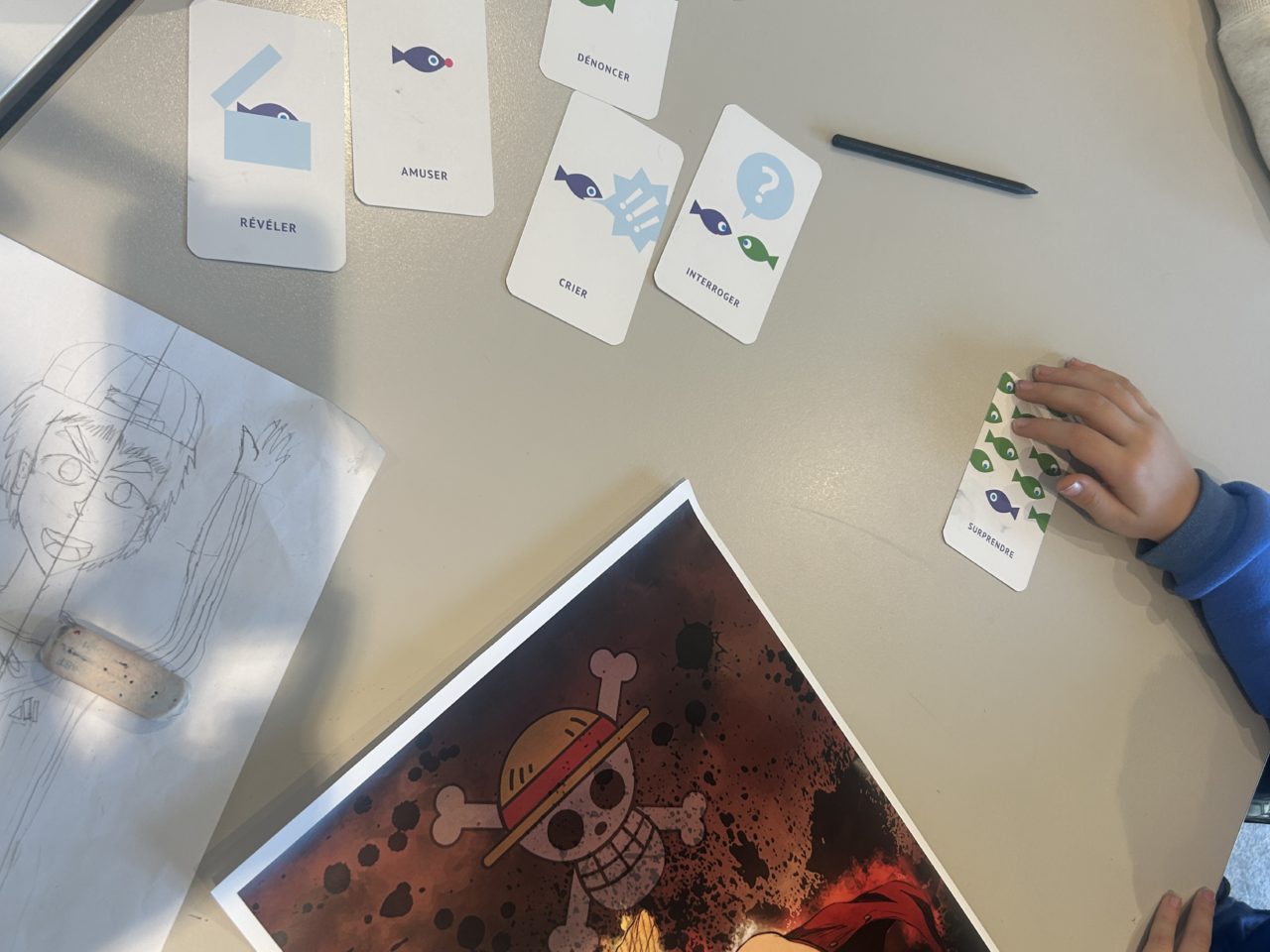 Images d'une main d'enfant ayant choisi l'une des cartes des "Mots du clic" un outil de lecture d'images.